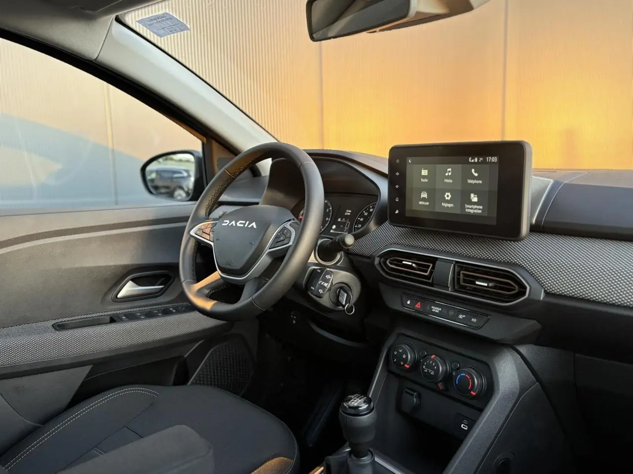 Intérieur avant droit du Dacia Sandero Stepway 2025, volant multifonction et écran tactile multimédia visible.