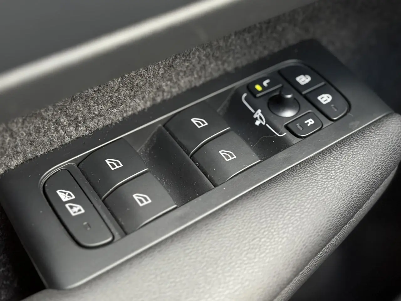 Panneau de commandes des vitres et rétroviseurs côté conducteur du Volvo XC40 B3 MHEV rouge Fusion, intérieur noir.