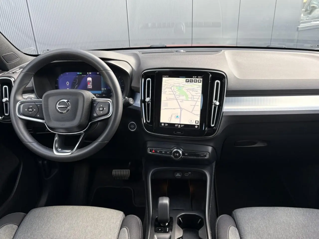 Intérieur du Volvo XC40 2024 vu de face, tableau de bord noir avec écran tactile central affichant la navigation.