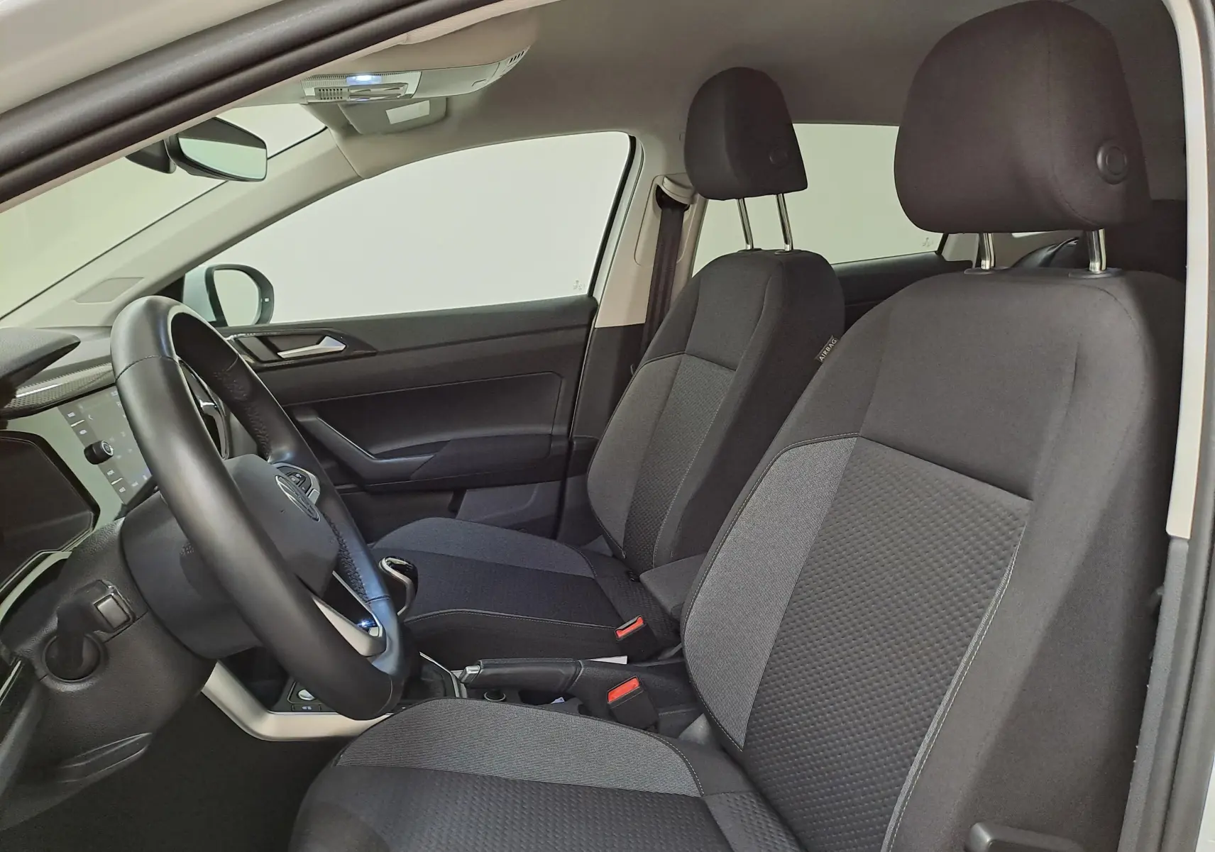 Vue intérieure côté gauche du Volkswagen Taigo 2024, montrant les sièges avant noirs et le volant cuir.