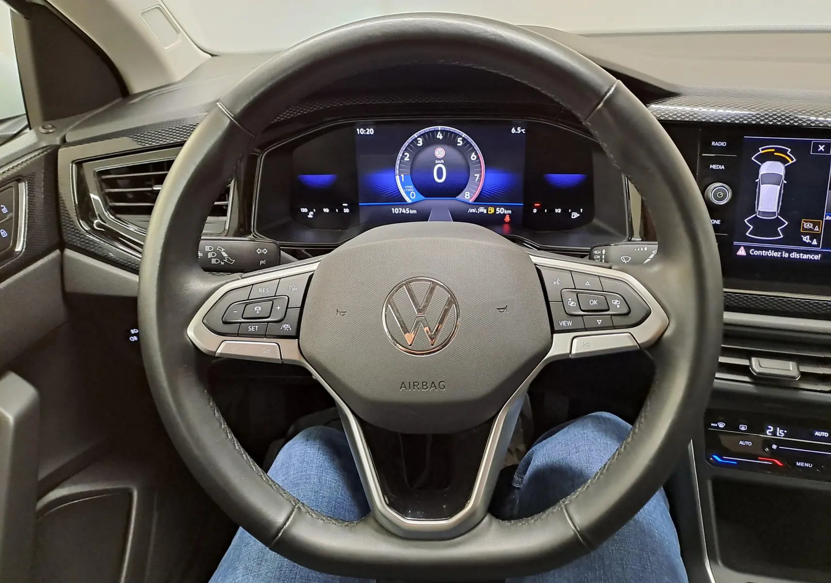 Vue intérieure centrée sur le volant noir du Volkswagen Taigo 2024 avec tableau de bord numérique et écran tactile.