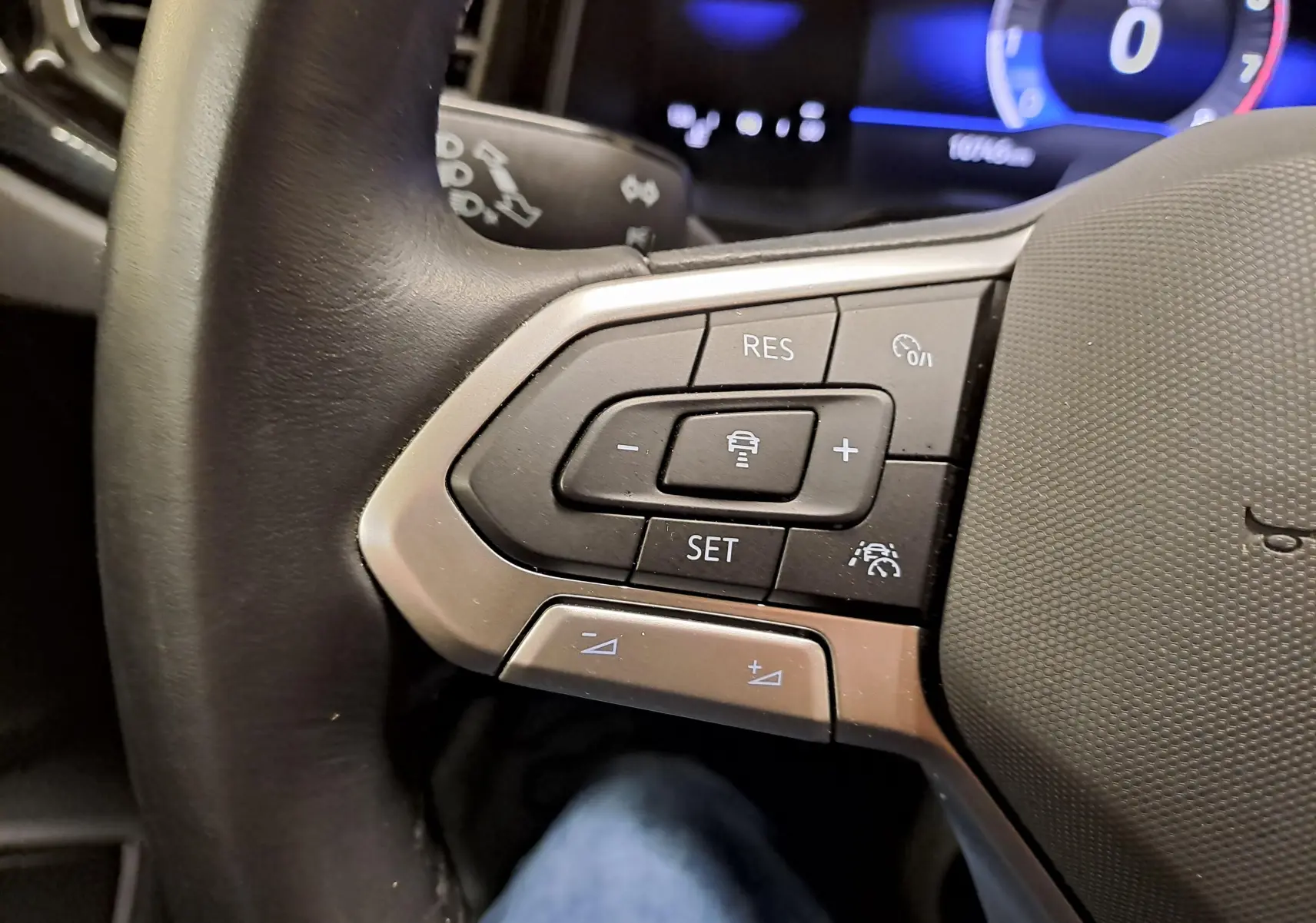 Gros plan sur les commandes au volant côté gauche du Volkswagen Taigo 2024, avec affichage numérique en arrière-plan.