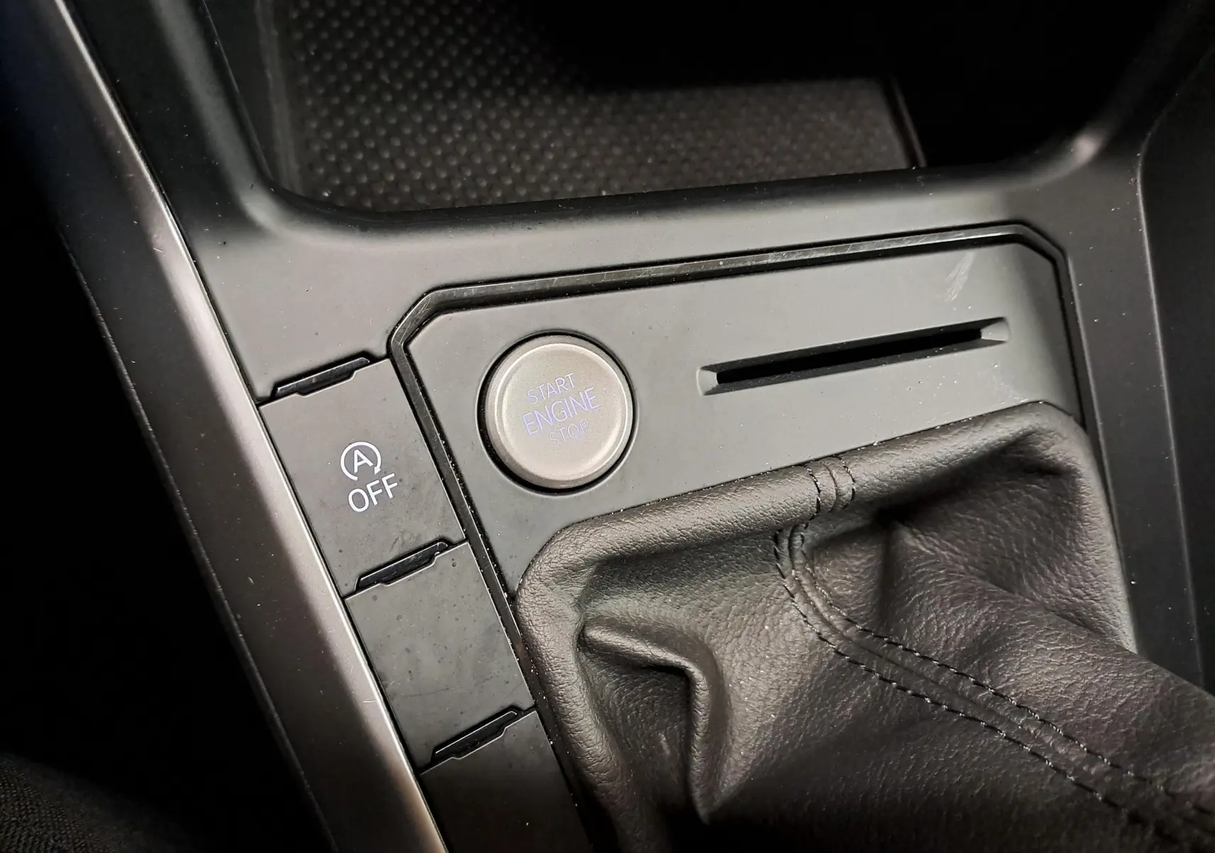 Gros plan sur la console centrale noire du Volkswagen Taigo 2024, avec bouton Start Engine et soufflet de levier de vitesse en cuir.