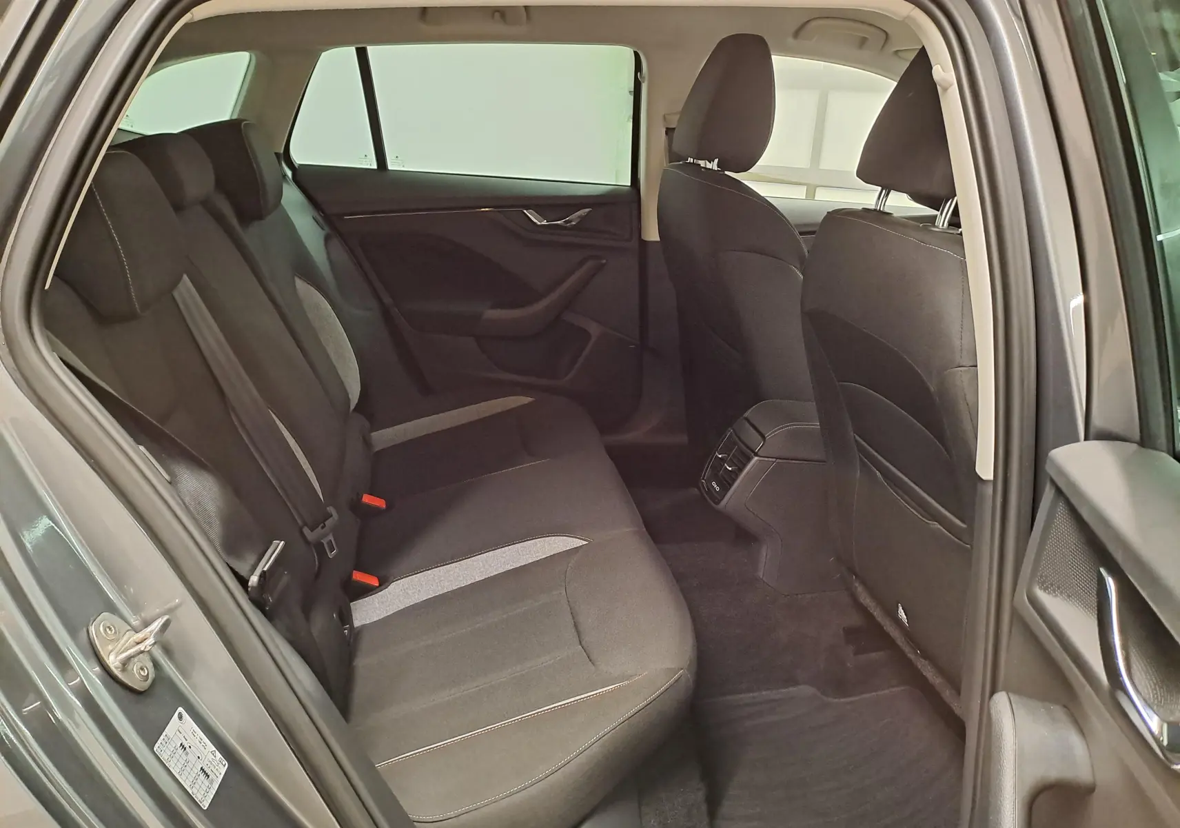 Vue intérieure côté gauche des sièges arrière du Skoda Scala 2025 gris graphite avec habillage tissu bicolore et aérateurs centraux.