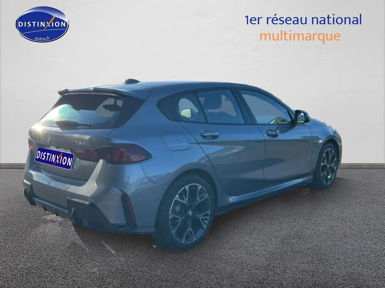 BMW Série 1 118da gris Skyscraper vue 3/4 arrière droit avec jantes 18 pouces bicolores et becquet M Sport Pro.