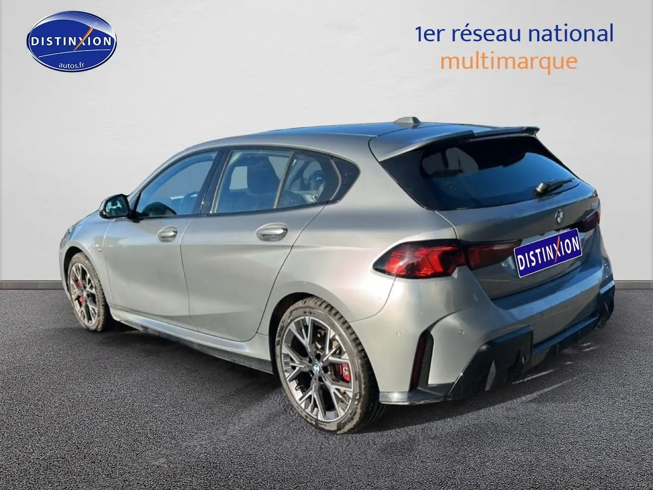 BMW Série 1 118da gris skyscraper vue 3/4 arrière droit avec jantes 18 pouces bicolores et becquet sportif.
