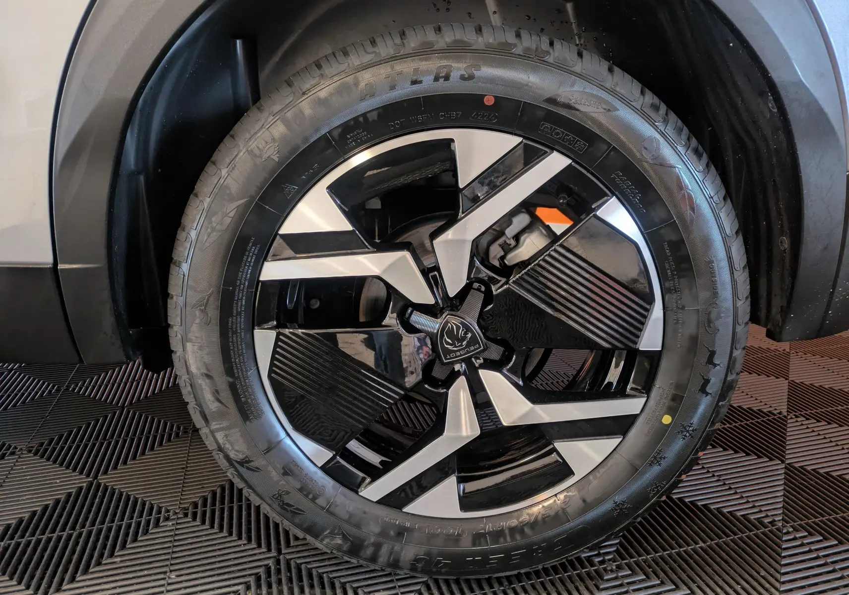 Gros plan sur la roue avant droite du Peugeot 2008 Hybrid 145 e-DCS6 GT avec jante bi-ton noire et argent.