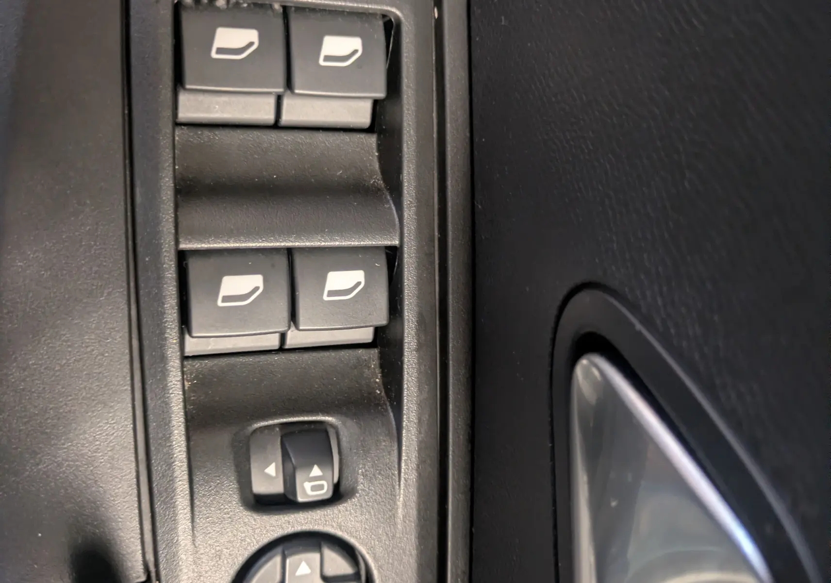 Gros plan sur les commandes des vitres électriques et rétroviseurs côté conducteur du Peugeot 2008 Hybrid 145 e-DCS6 GT 2025.