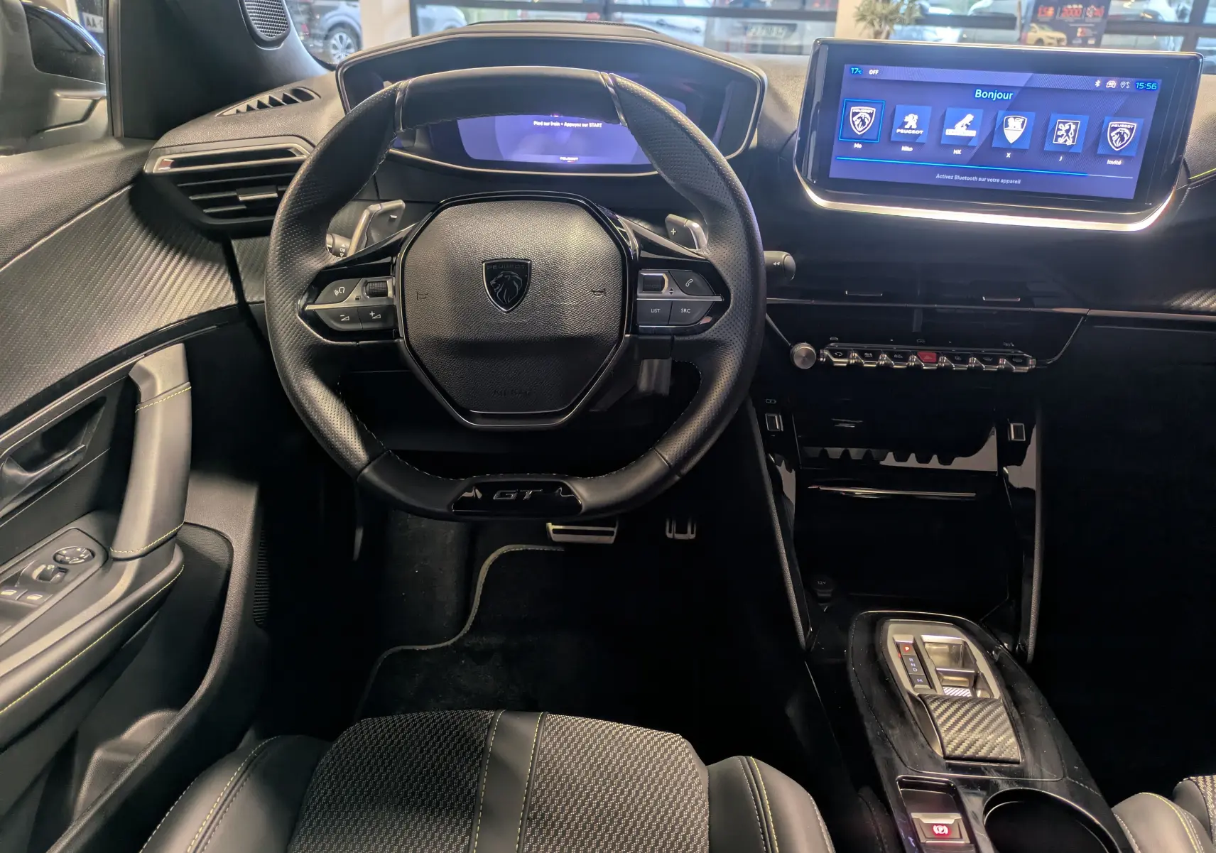 Vue intérieure avant du Peugeot 2008 Hybrid 145 e-DCS6 GT, avec volant GT, écran tactile et finitions noires.