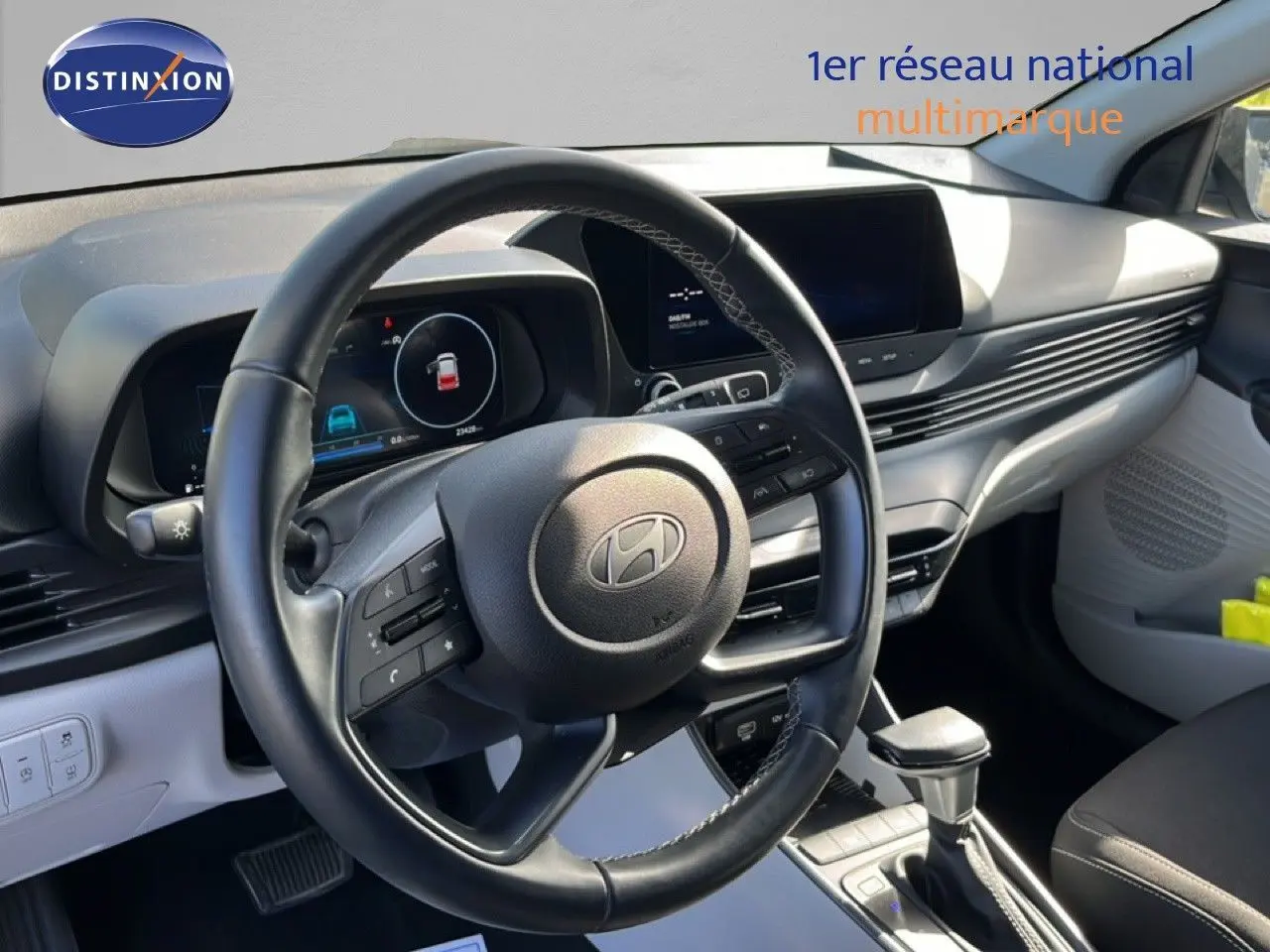 Vue intérieure du poste de conduite de la Hyundai i20 2025, volant cuir noir et tableau de bord gris aurora metal.