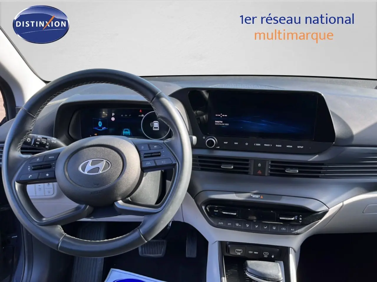 Vue intérieure du tableau de bord et volant de la Hyundai i20 2025 en gris Aurora Metal, avec écran tactile et commandes au volant.