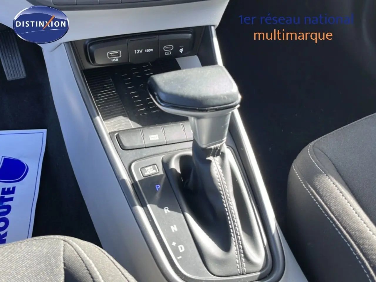Gros plan sur la console centrale de la Hyundai i20 2025 gris aurora, mettant en valeur le levier de vitesses automatique et les ports USB.
