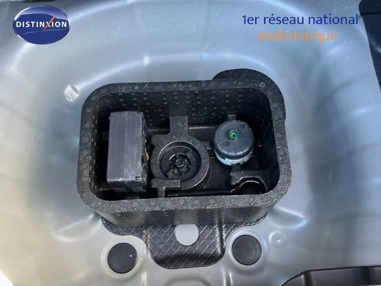 Vue en plongée sur le compartiment de rangement gris Aurora métal d'une Hyundai i20 2025, montrant les outils intégrés.