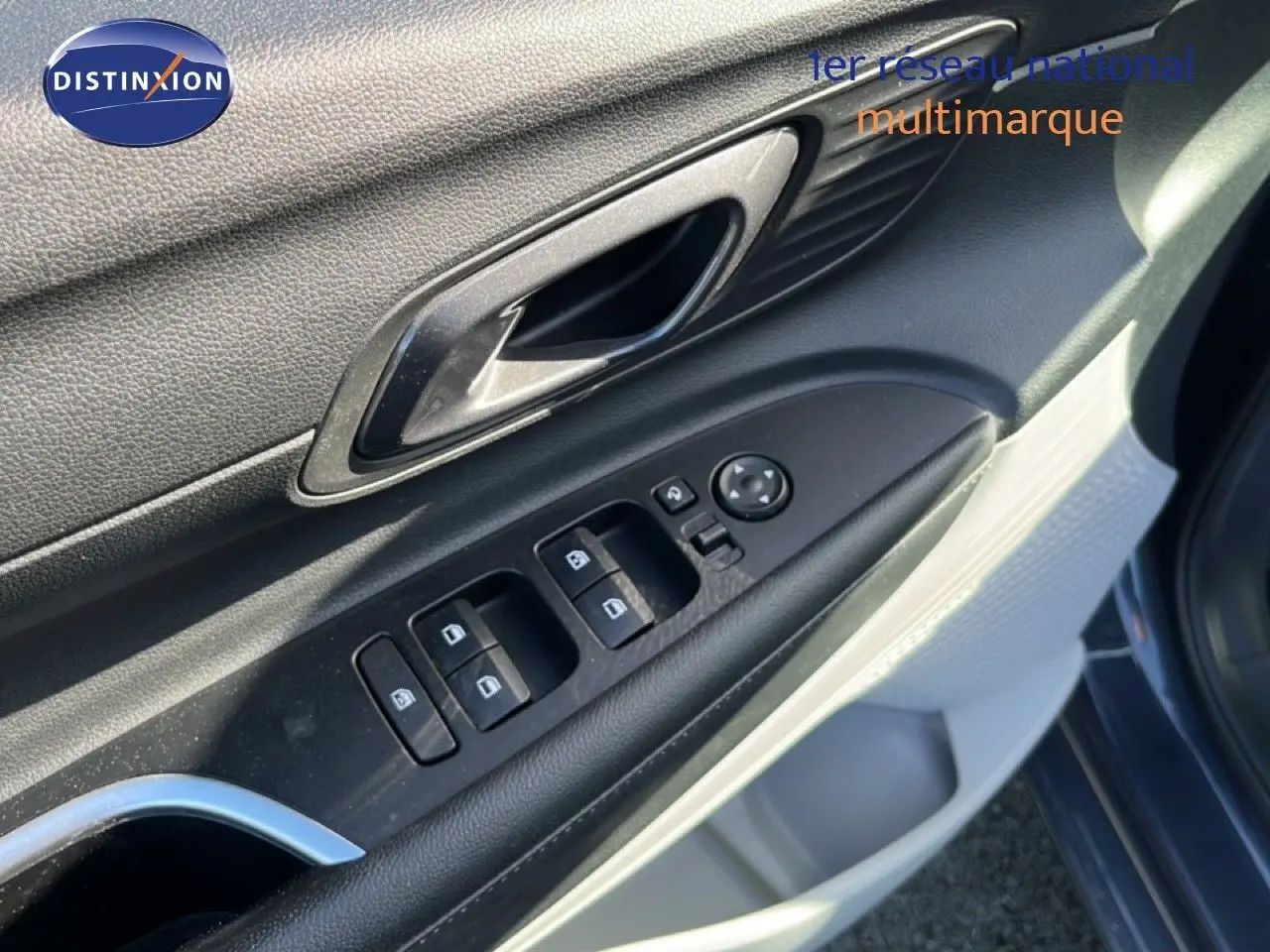 Gros plan sur la porte côté gauche de la Hyundai i20 gris Aurora Metal, montrant les commandes des vitres et la poignée intérieure.