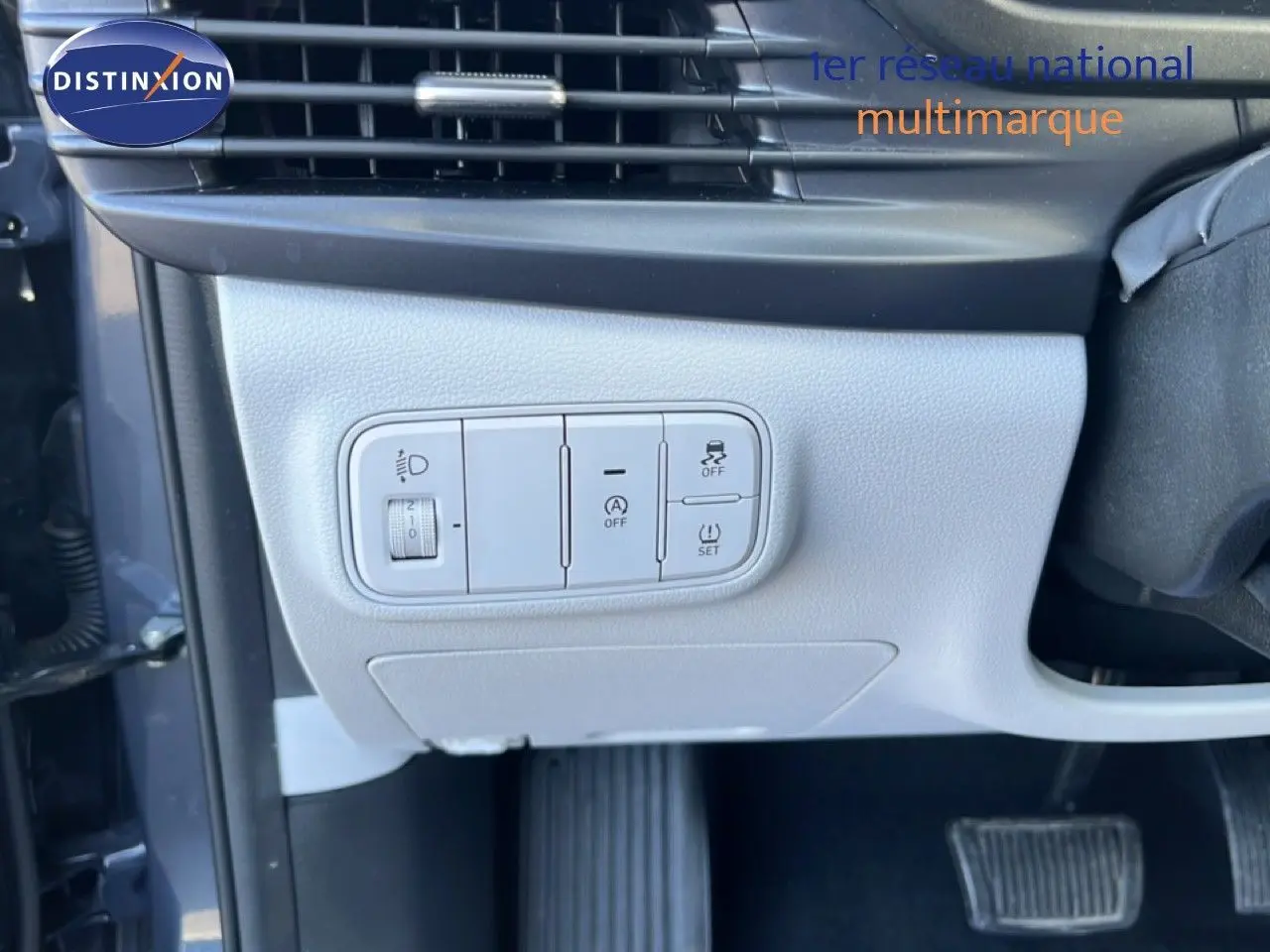 Gros plan sur les commandes de réglage des phares et aides à la conduite côté gauche d’un Hyundai i20 gris Aurora 2025.