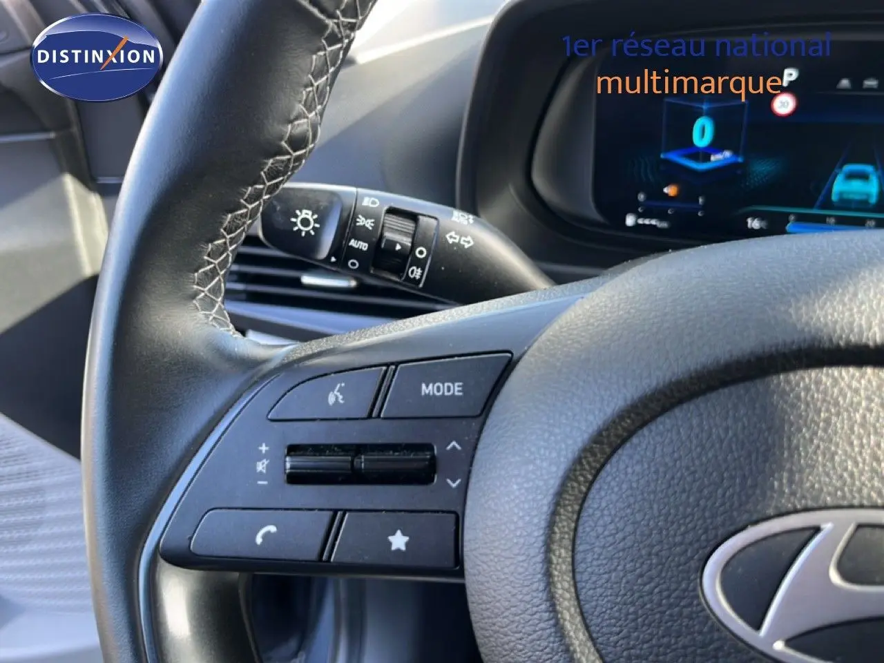 Gros plan sur le volant cuir gris avec commandes multifonctions de la Hyundai i20 2025 en intérieur.