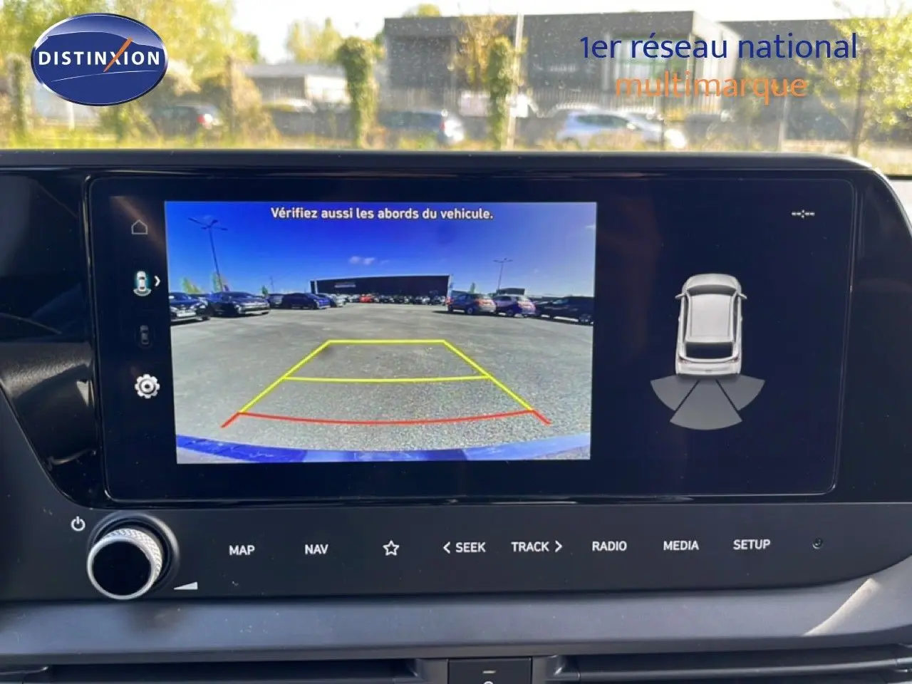 Écran central de la Hyundai i20 2025 montrant la caméra de recul avec lignes de guidage colorées en extérieur.