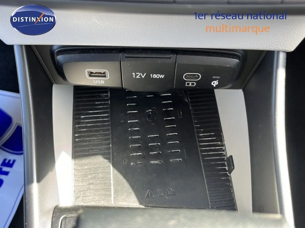 Vue rapprochée de la console centrale de la Hyundai i20 2025, montrant les ports USB, prise 12V et chargeur sans fil noir.