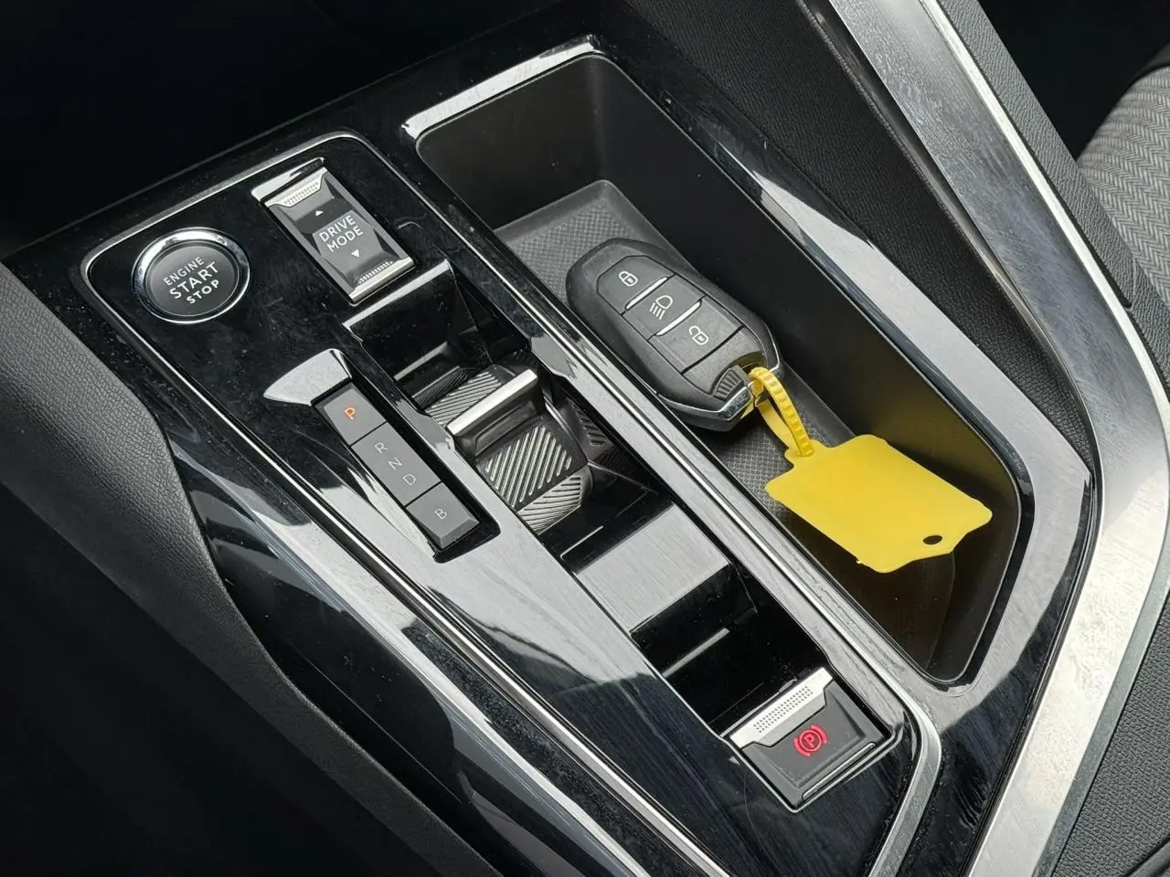 Vue rapprochée de la console centrale noire brillante du Peugeot 3008 Plug-in Hybrid avec clé et bouton start/stop.