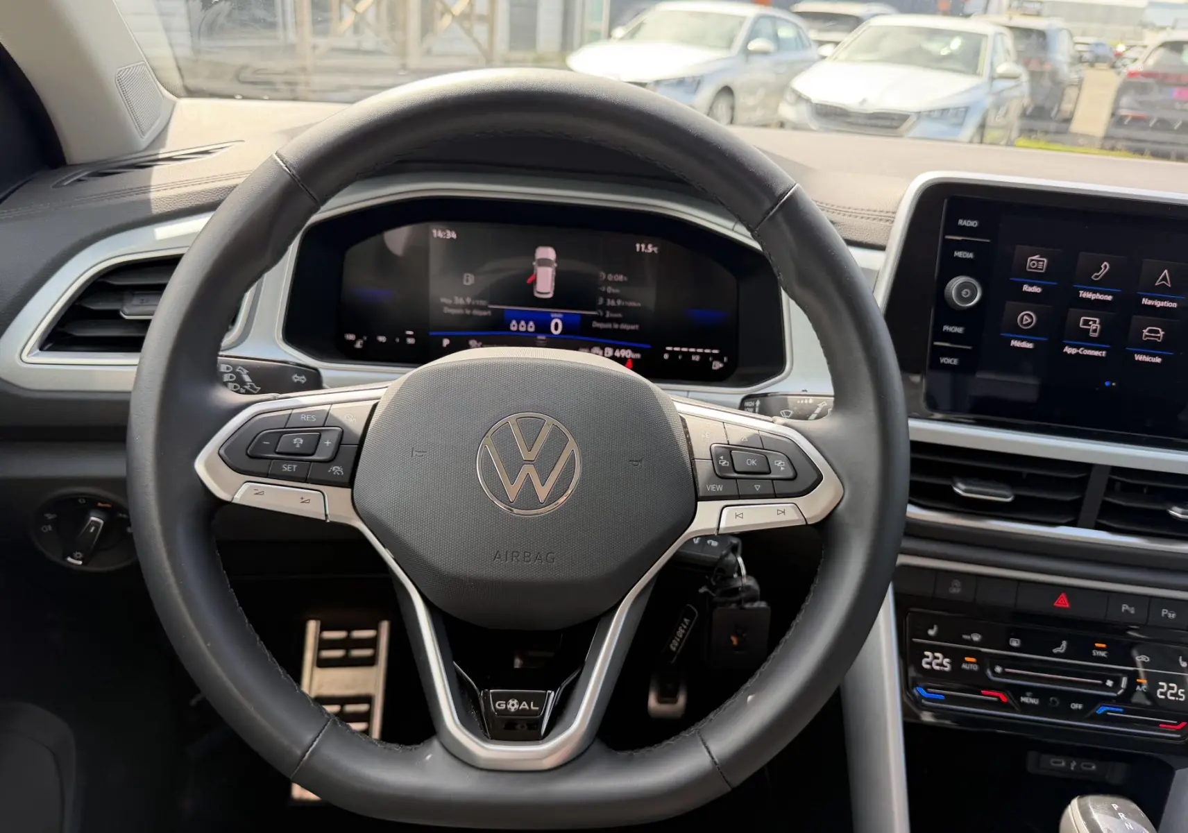 Vue intérieure centrée sur le volant multifonction en cuir du Volkswagen T-Roc avec tableau de bord digital et écran tactile.