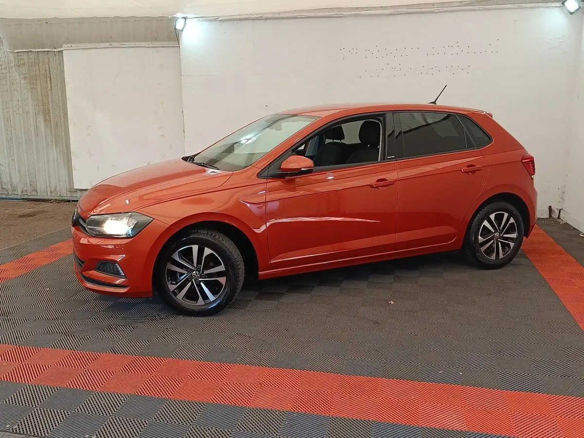 Volkswagen Polo 1.0 TSI orange vue de profil côté gauche, phares allumés, jantes alliage noires et argentées.