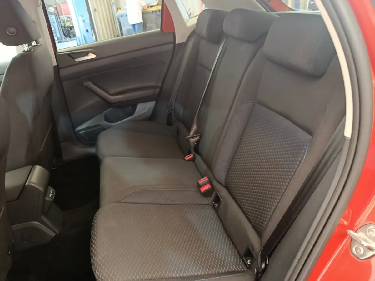 Vue intérieure côté droit des sièges arrière noirs d'une Volkswagen Polo orange, avec ceinture de sécurité visible.