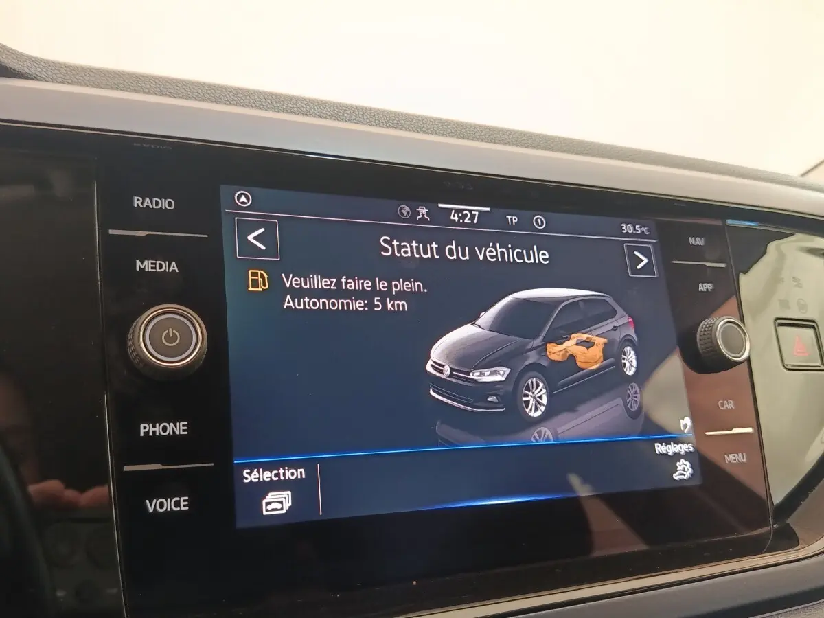 Écran tactile intérieur affichant le statut d'une Volkswagen Polo 1.0 TSI avec message d'autonomie faible.