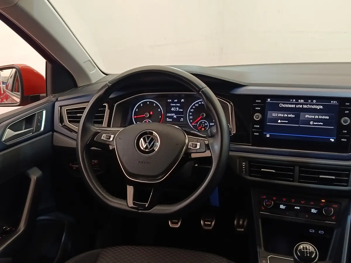 Vue intérieure centrée sur le volant cuir alu et tableau de bord numérique de la Volkswagen Polo orange 2020.