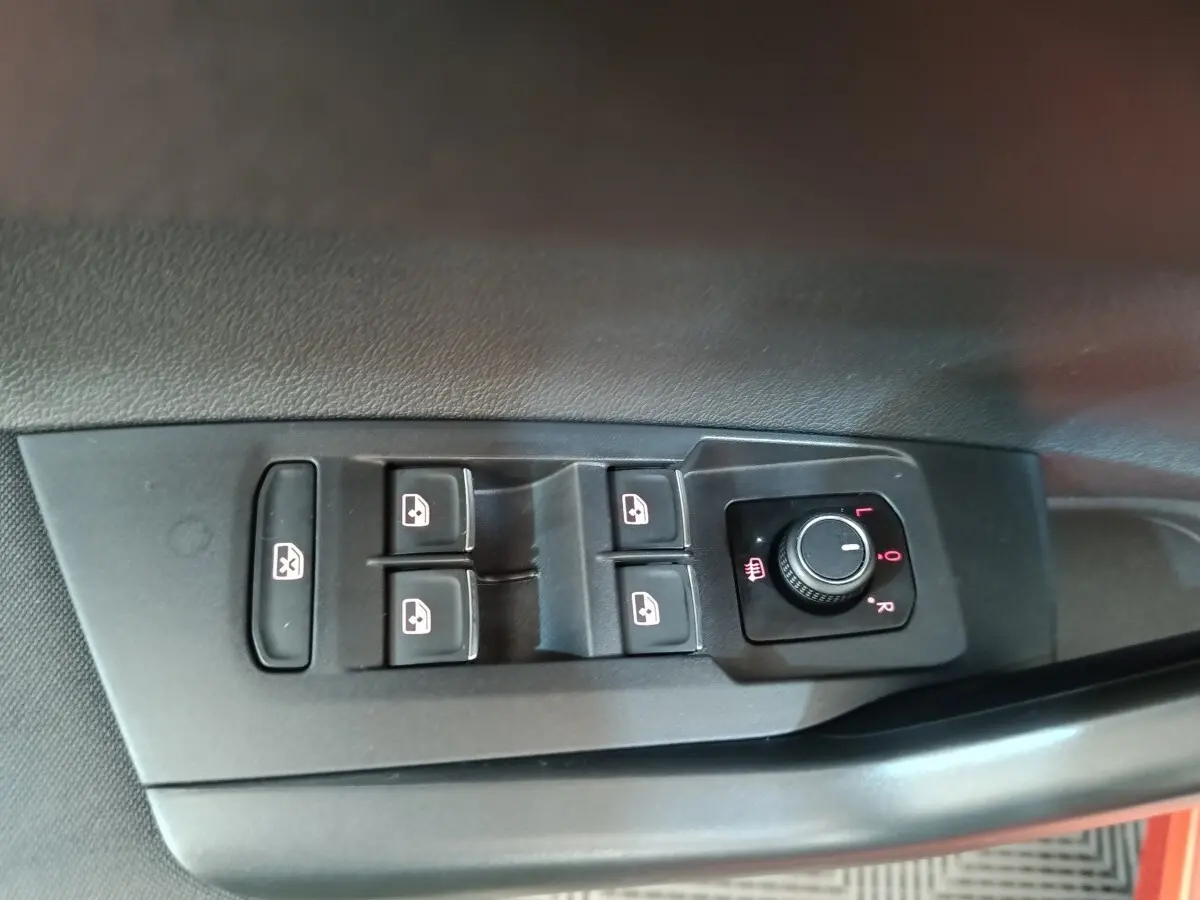 Commande des vitres électriques et réglage des rétroviseurs sur la porte côté conducteur d’une Volkswagen Polo orange.