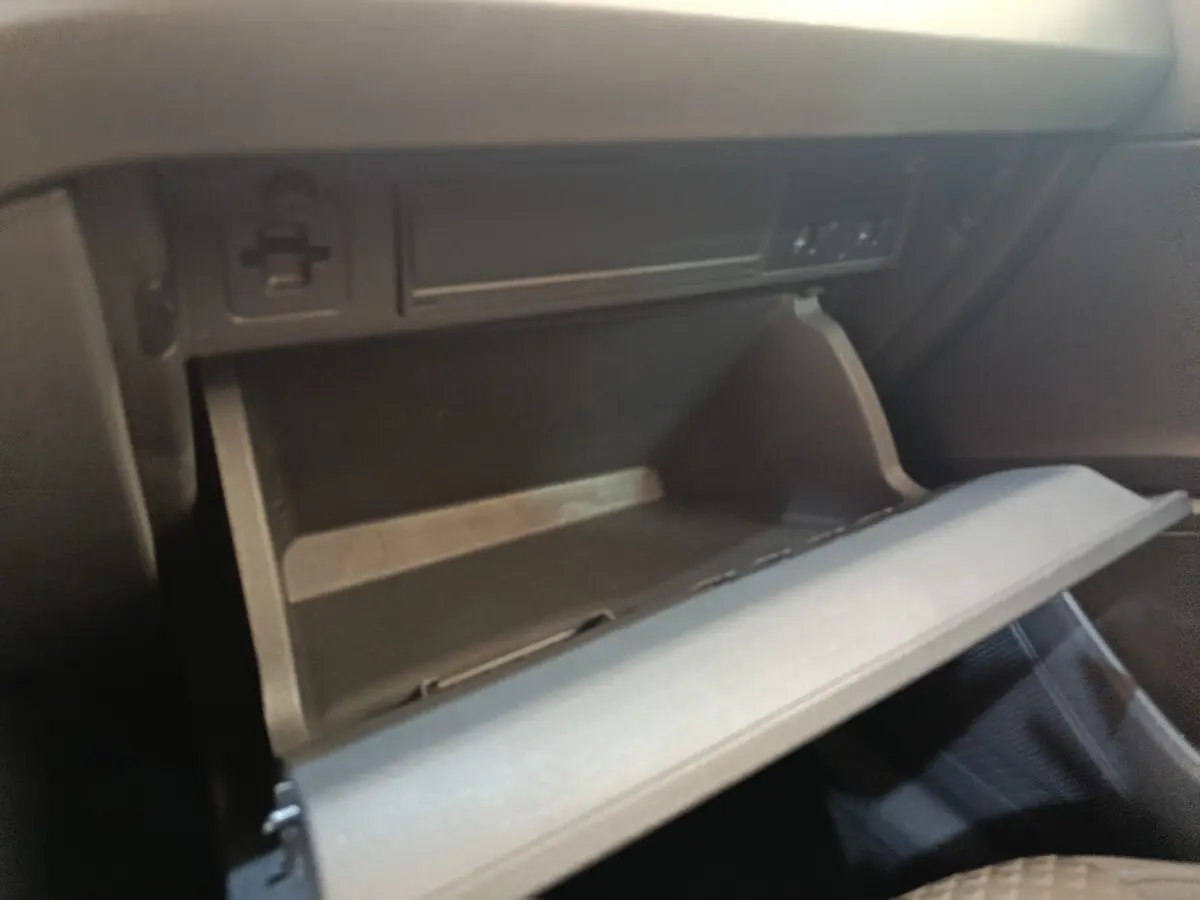 Gros plan sur la boîte à gants ouverte côté passager dans l'habitacle noir d'une Volkswagen Polo orange 2020.