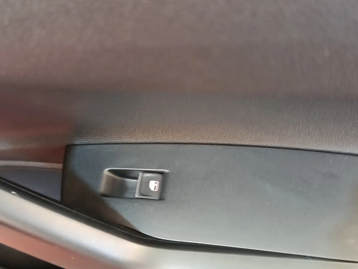 Détail du bouton de verrouillage des portes sur la porte intérieure côté conducteur d'une Volkswagen Polo orange.