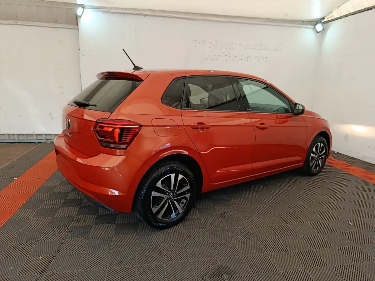 Volkswagen Polo 1.0 TSI 95 United orange vue 3/4 arrière droit dans un garage avec jantes noires et argentées.