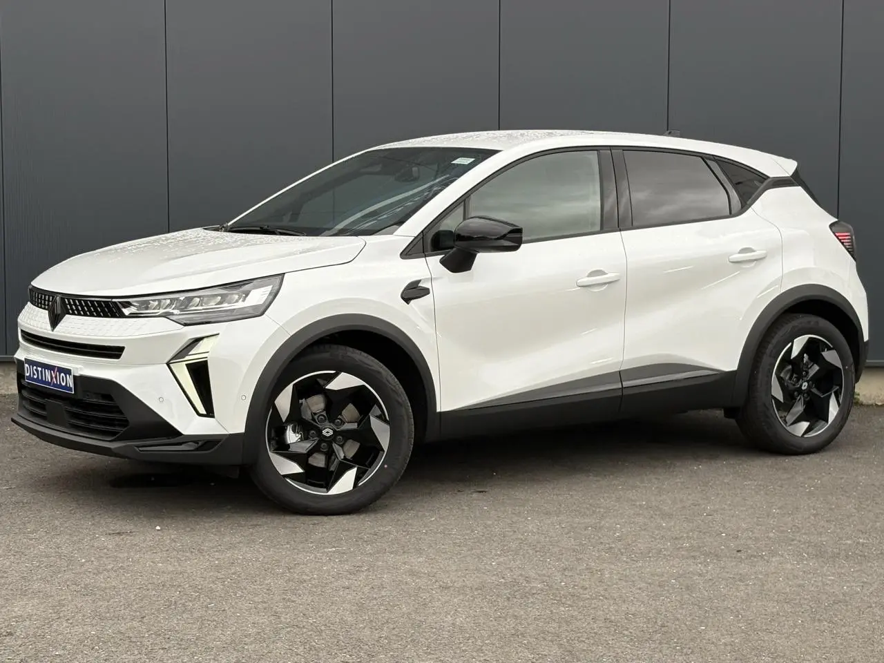 Vue de profil droit du Renault Captur blanc nacré 2026 avec jantes noires et détails noirs contrastants.