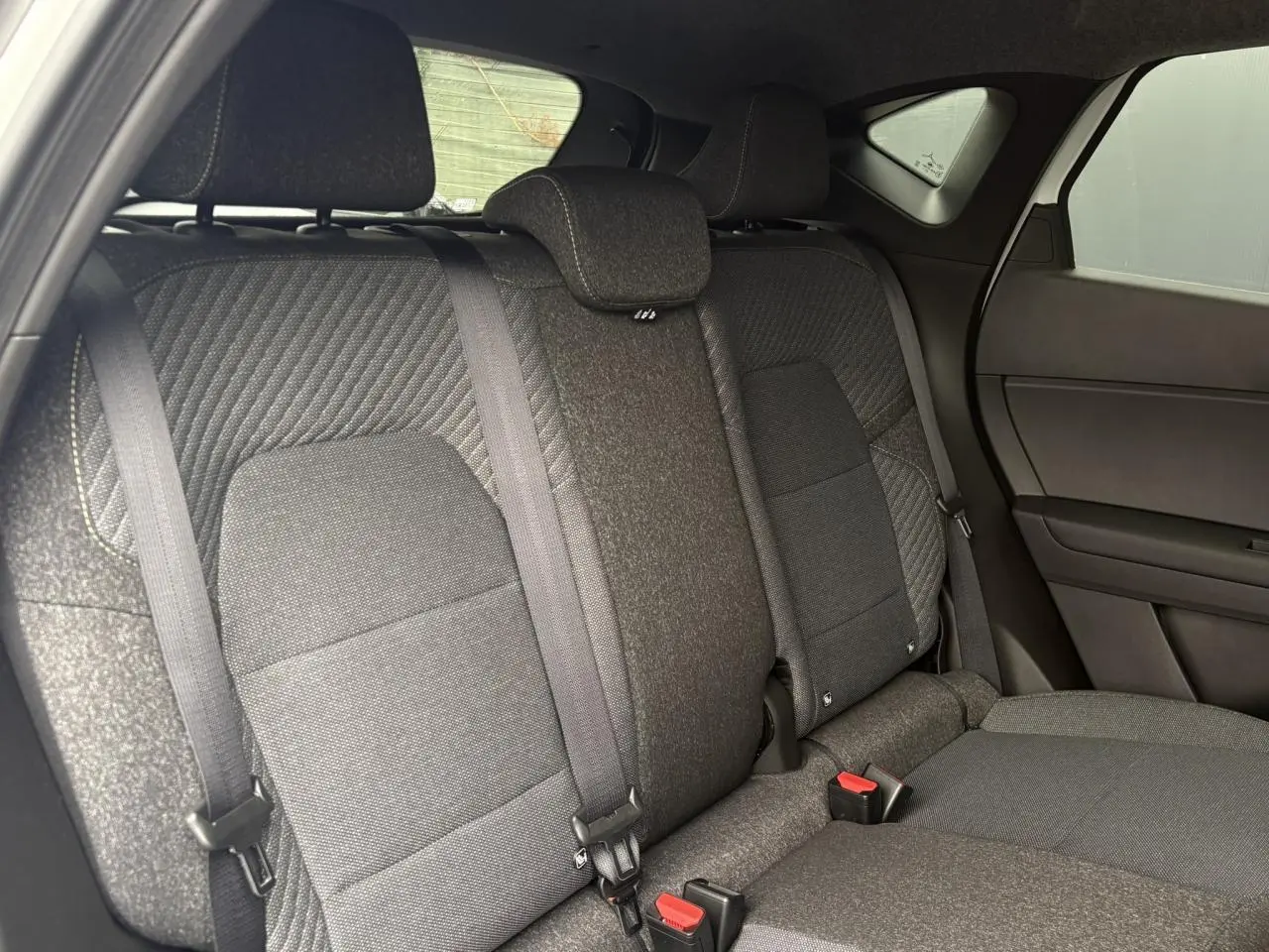 Vue intérieure du siège arrière droit du Renault Captur 2026 en tissu gris foncé avec ceinture de sécurité.