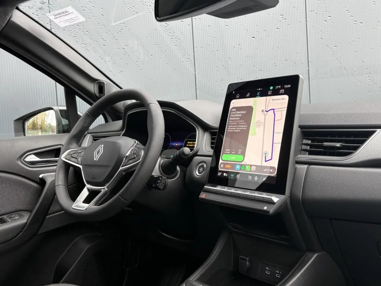 Vue intérieure du tableau de bord du Renault Captur blanc nacré, avec écran tactile vertical et volant multifonction.