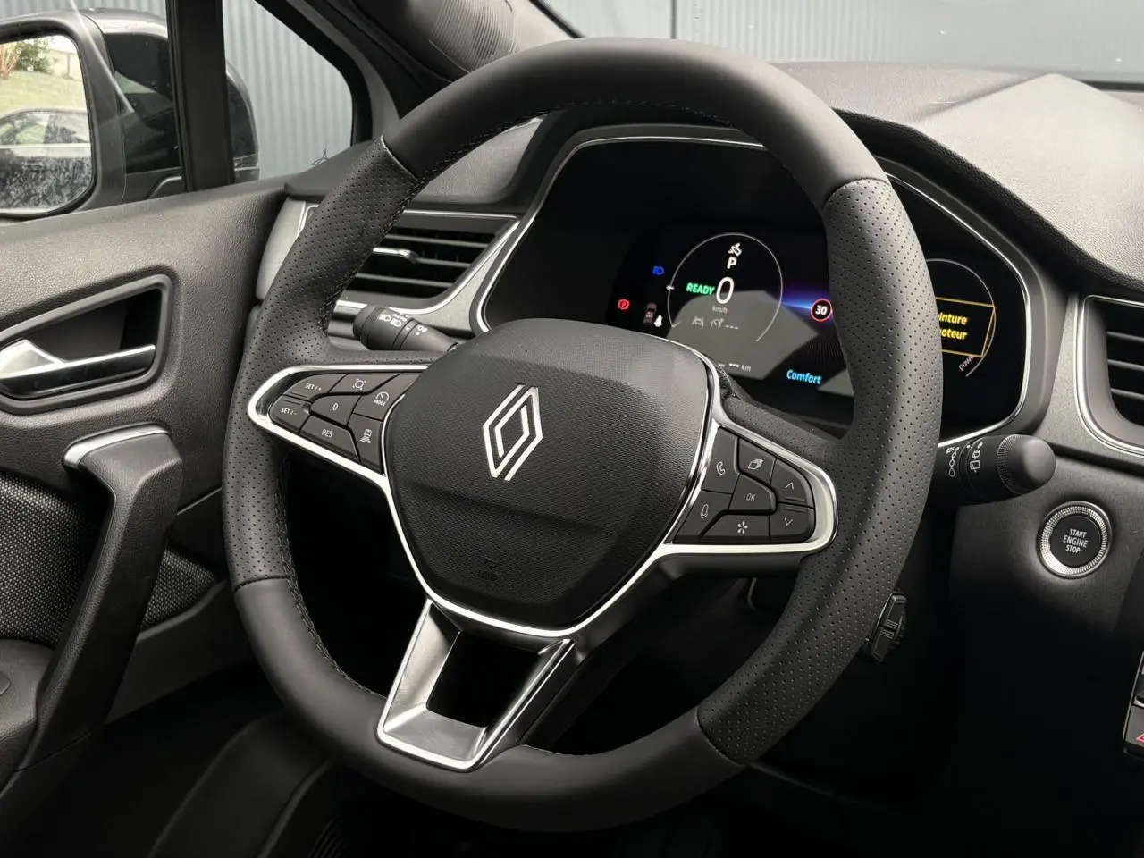 Vue rapprochée du volant noir perforé et du tableau de bord numérique du Renault Captur hybride 2026.