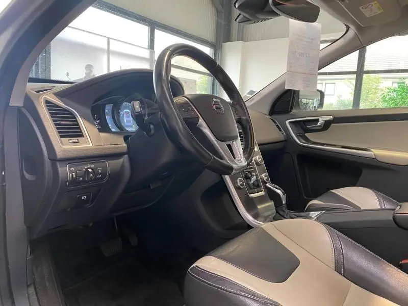 Intérieur du Volvo XC60 D4 2015 vu côté conducteur, volant cuir multifonction et sièges bicolores gris et noir.