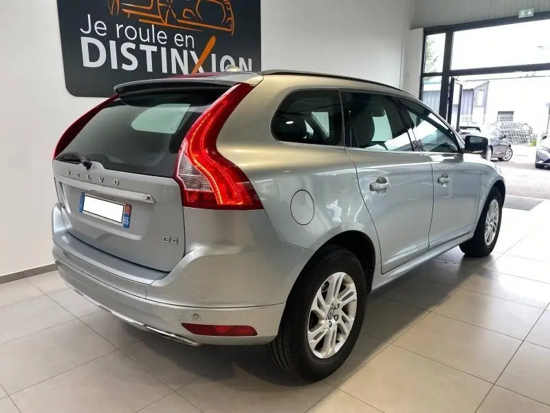 Vue 3/4 arrière droite d'un Volvo XC60 D4 argenté avec feux arrière LED et jantes alliage en showroom.