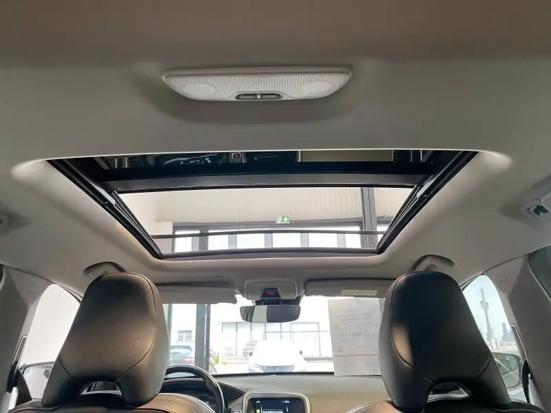 Vue intérieure avant du Volvo XC60 argenté 2015, mettant en valeur le toit ouvrant panoramique et les sièges en cuir noir.