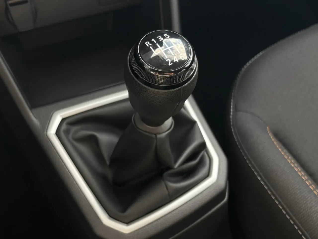 Le levier de vitesse manuel noir de la Dacia Sandero Stepway 2025 avec coutures marron sur siège côté droit.