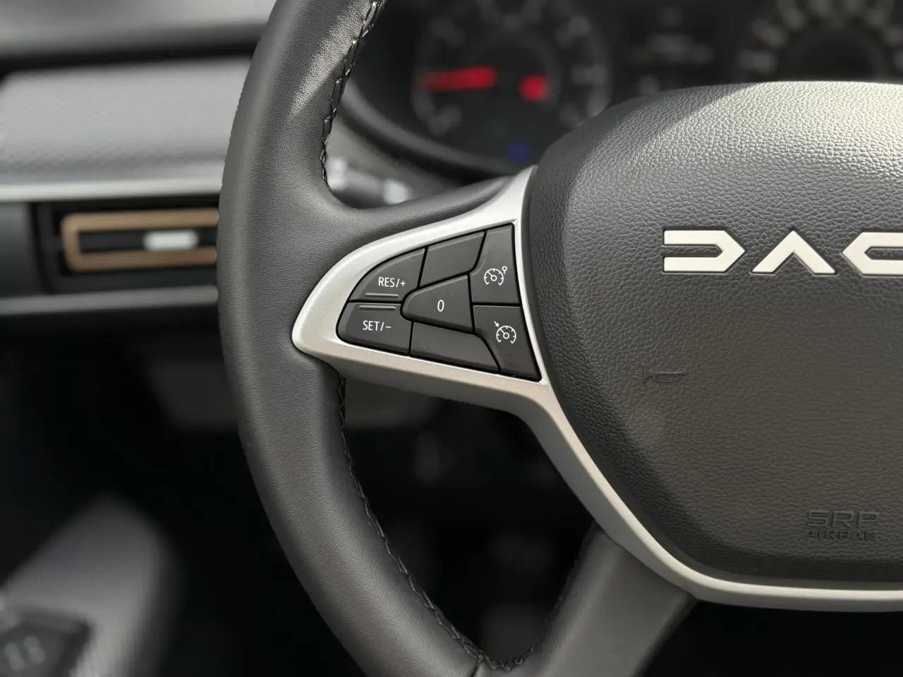 Gros plan sur le volant noir de la Dacia Sandero Stepway 2025 avec commandes de régulateur de vitesse intégrées.