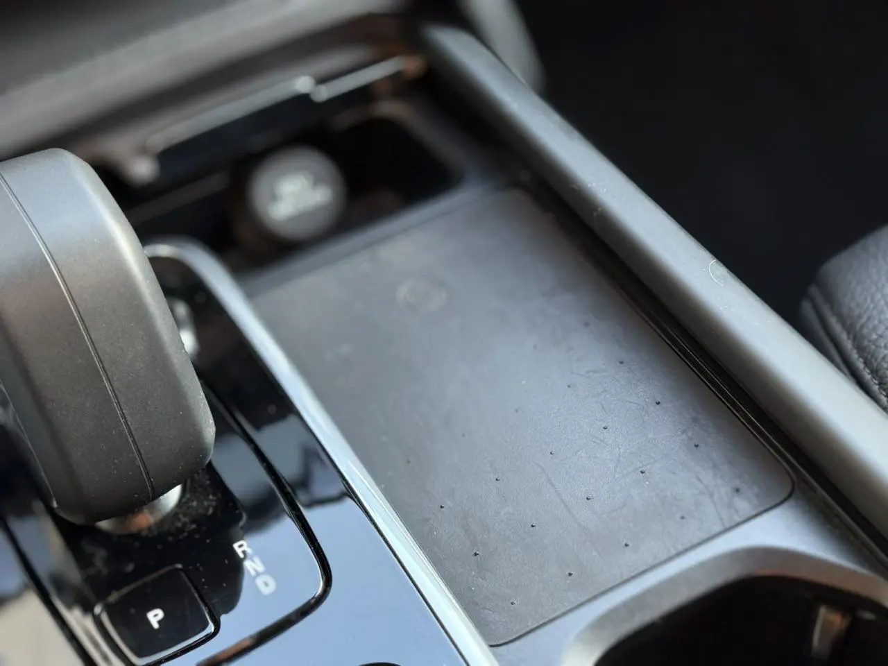 Gros plan sur la console centrale noire du Volvo XC90 T8 hybride 2024 avec levier de vitesses automatique et chargeur induction.