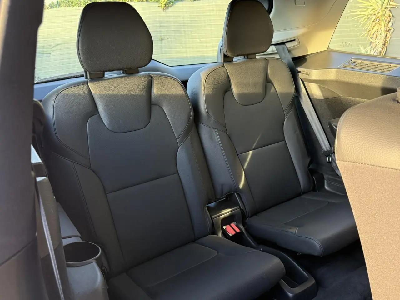 Vue intérieure sur les sièges noirs de la troisième rangée du Volvo XC90 T8 AWD 2024 en lumière naturelle.