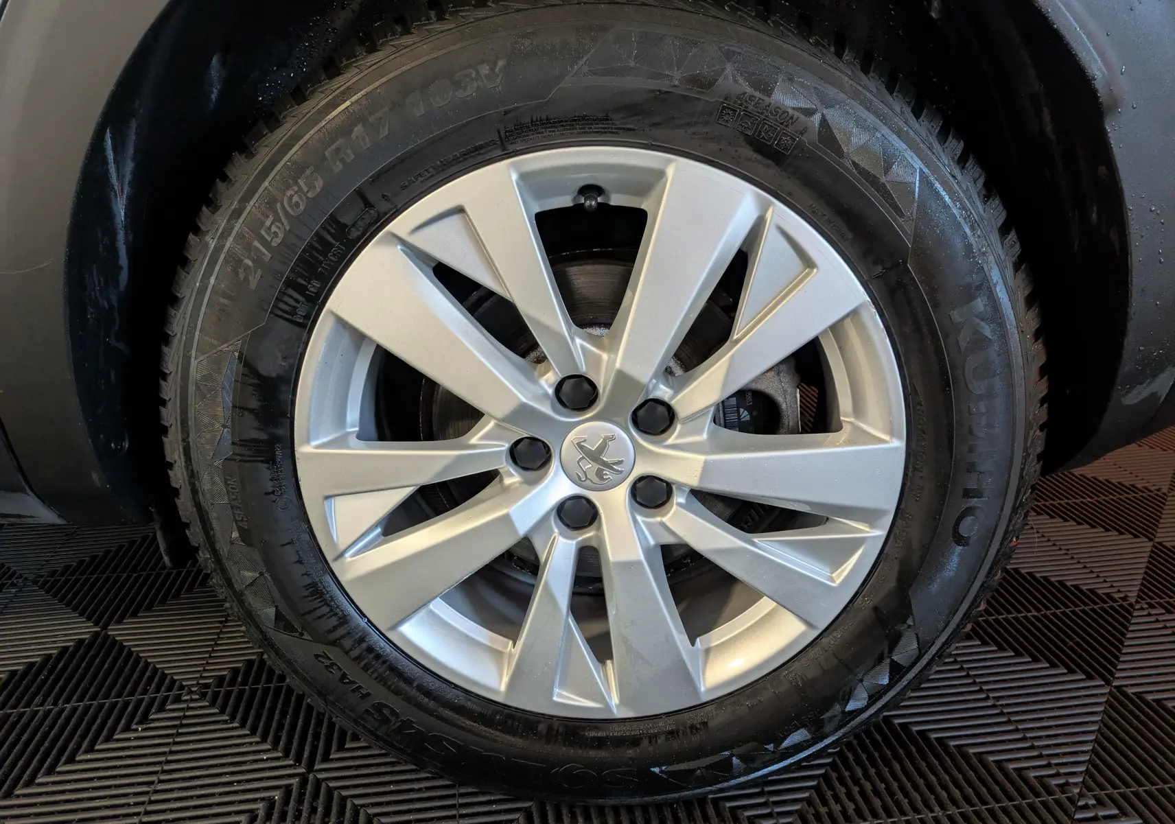 Gros plan sur la jante argentée d’une Peugeot 3008 gris Arthense, mettant en valeur le logo lion central.