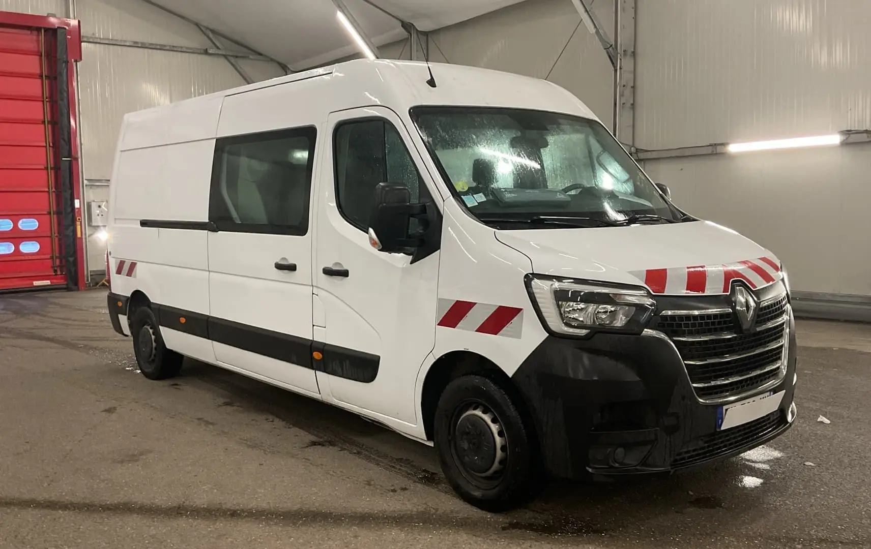 Renault Master cabine approfondie blanc en 3/4 avant droit avec bandes rouges de signalisation sur capot et ailes.