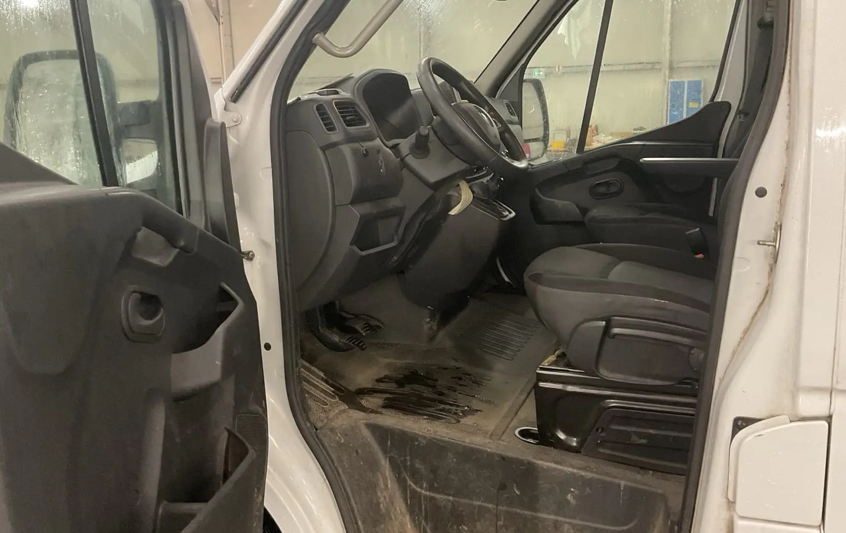 Vue intérieure côté conducteur du Renault Master blanc 2020, montrant le tableau de bord et les sièges avant en tissu noir.
