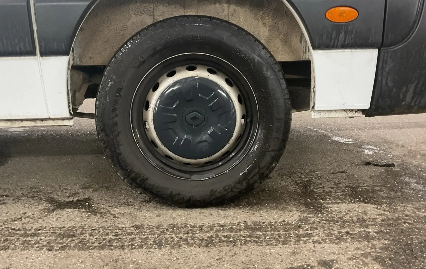 Gros plan sur la roue arrière droite d’un Renault Master cabine approfondie blanc, avec pare-boue et feu latéral orange.