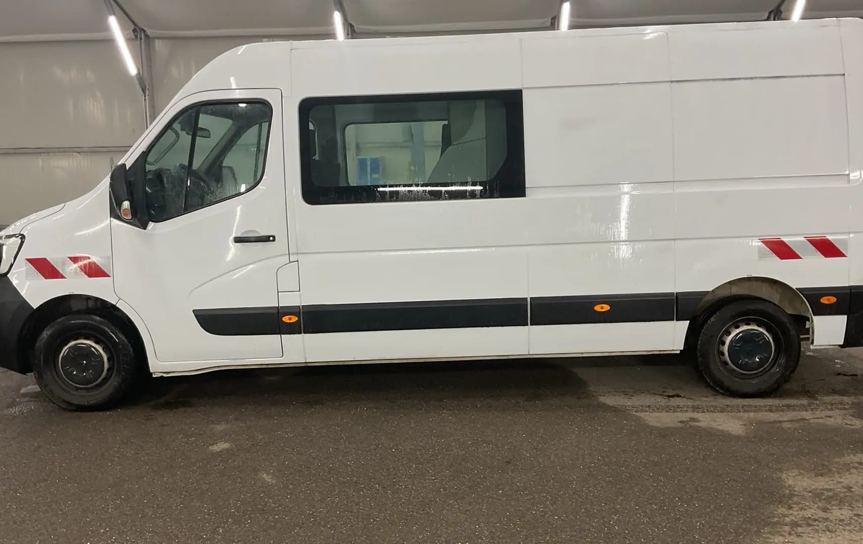 Vue de profil côté gauche d’un Renault Master blanc avec marquages rouges réfléchissants sur les ailes avant et arrière.