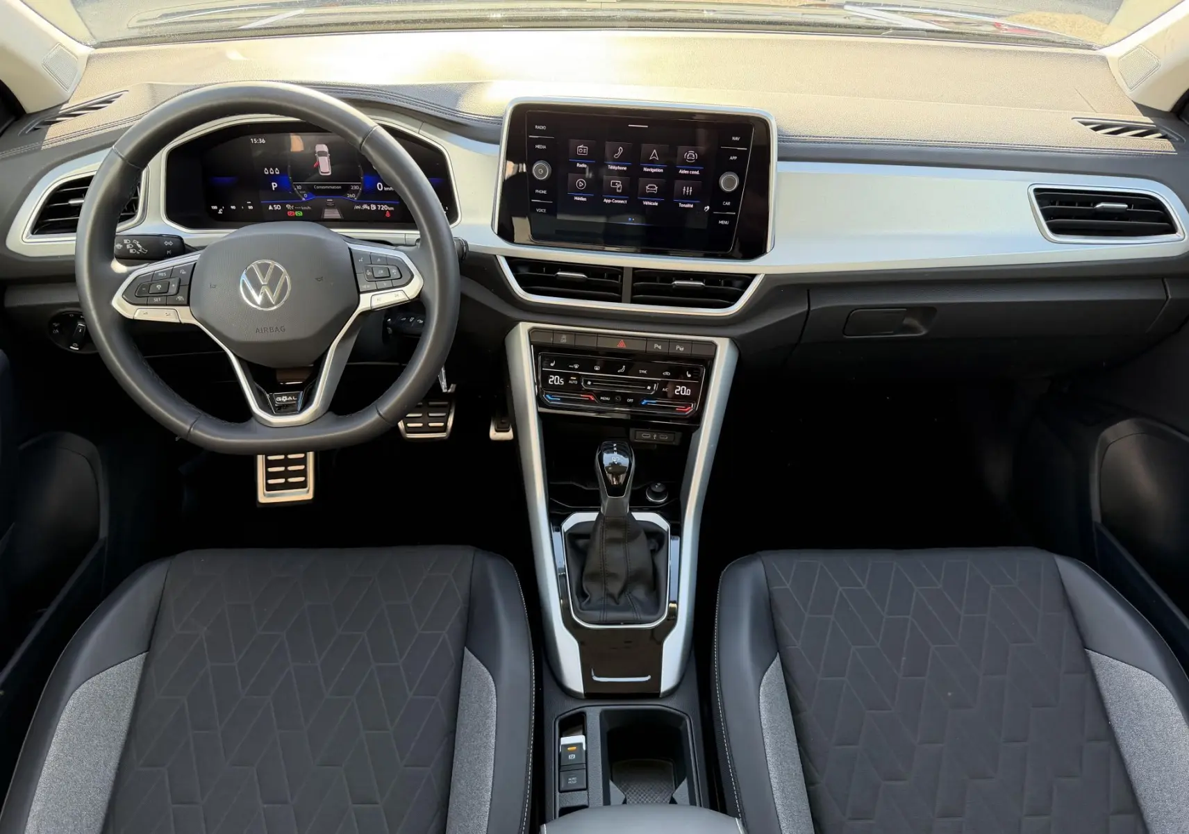 Vue intérieure frontale du tableau de bord et volant cuir noir du Volkswagen T-Roc 2025 avec écran tactile central et levier de vitesse.