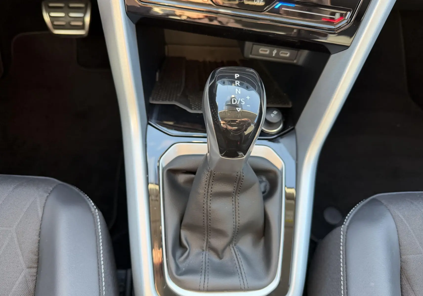 Vue rapprochée du levier de vitesses DSG7 noir et gris du Volkswagen T-Roc 2025, entouré des sièges avant en cuir noir.
